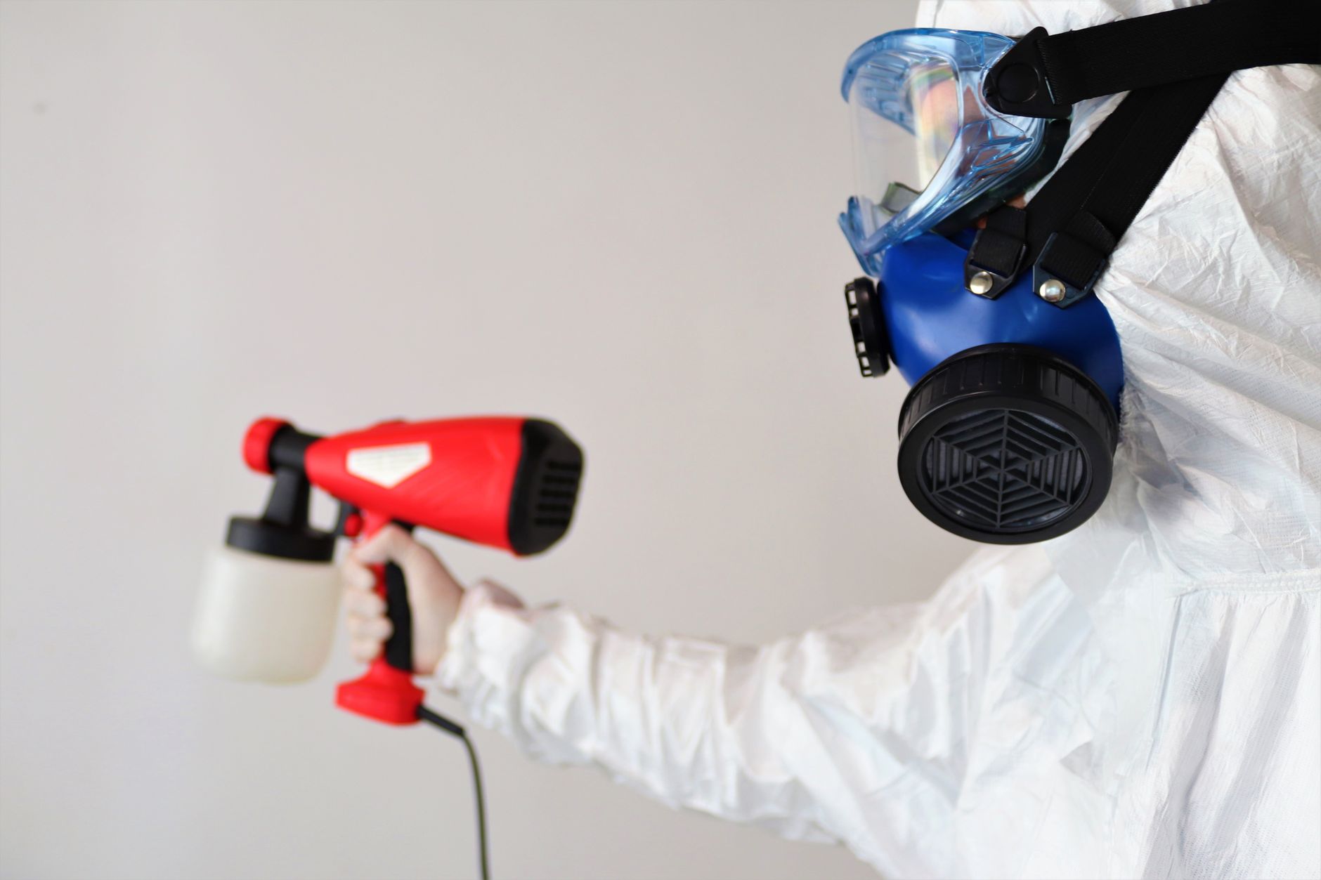 IICRC certified mold remediation technician inspecting a wall in a Freeport home, wearing protective gear and using a moisture meter.